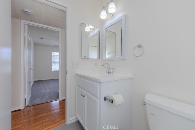 23222 Orange Ave Unit 4, Lake Forest, CA 92630 - bathroom featuring a textured ceiling, vanity, toilet, wood finished floors, and baseboards