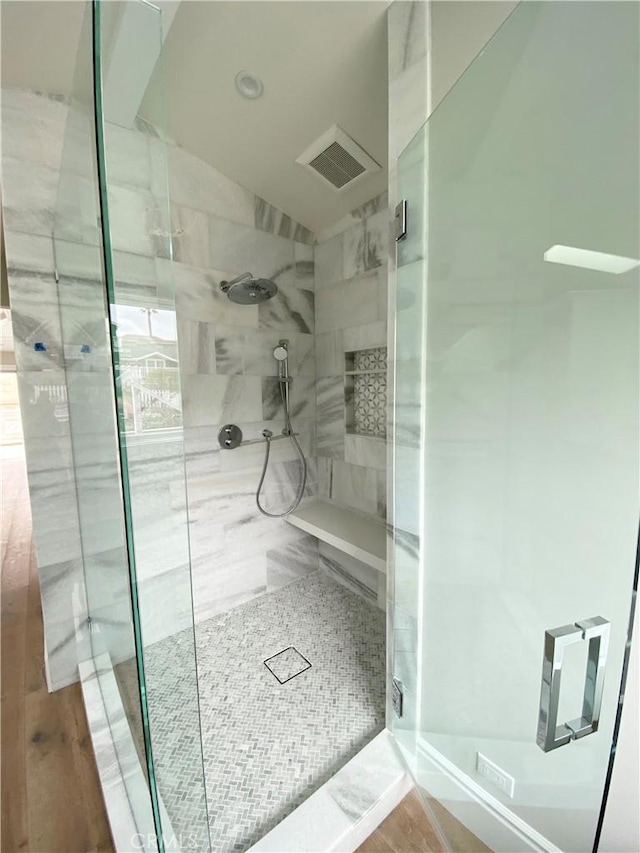 bathroom featuring visible vents, a shower stall, wood finished floors, and vaulted ceiling