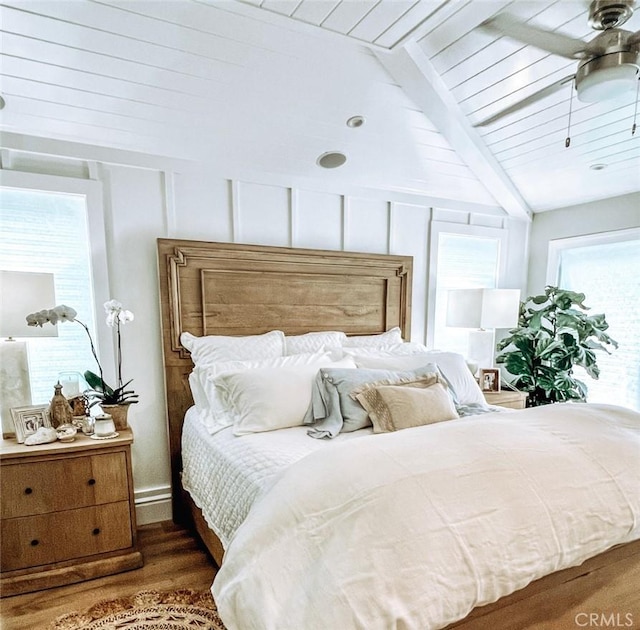 bedroom featuring ceiling fan, wood finished floors, and lofted ceiling with beams