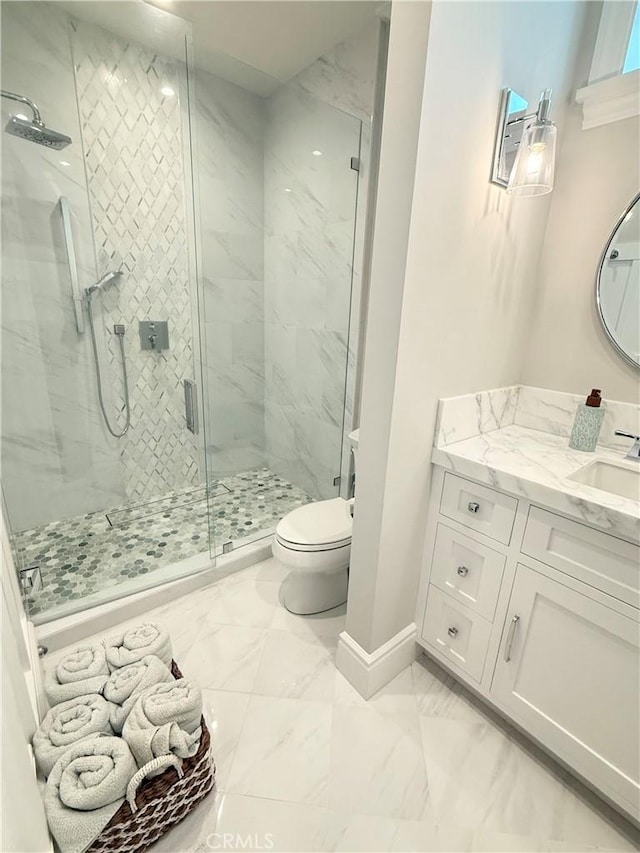 bathroom with vanity, toilet, marble finish floor, a marble finish shower, and baseboards