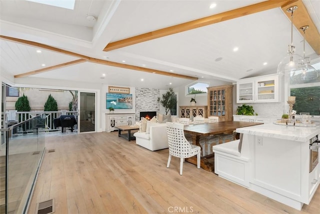 66 S La Senda Dr, Laguna Beach, CA 92651 - kitchen featuring light stone countertops, light wood-style floors, vaulted ceiling with beams, recessed lighting, and white cabinets
