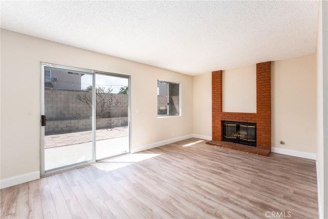 1076 N Ironwood Ave, Rialto, CA 92376 - unfurnished living room featuring a textured ceiling, wood finished floors, baseboards, and a brick fireplace