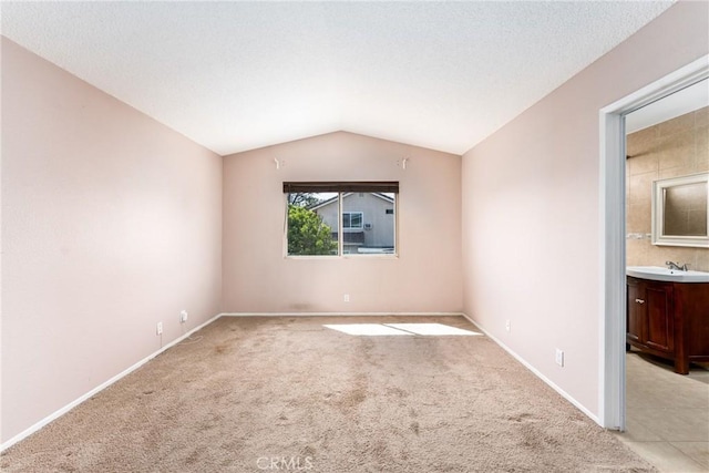 1076 N Ironwood Ave, Rialto, CA 92376 - empty room with a textured ceiling, baseboards, light carpet, a sink, and vaulted ceiling