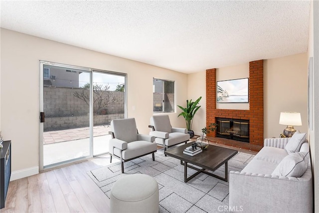 1076 N Ironwood Ave, Rialto, CA 92376 - living room featuring a textured ceiling, a fireplace, baseboards, and light wood-type flooring
