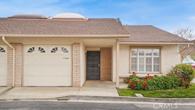 exterior space featuring a garage, stucco siding, and a shingled roof