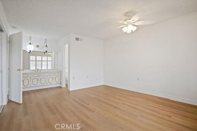 interior space featuring wood finished floors, ceiling fan, baseboards, and visible vents