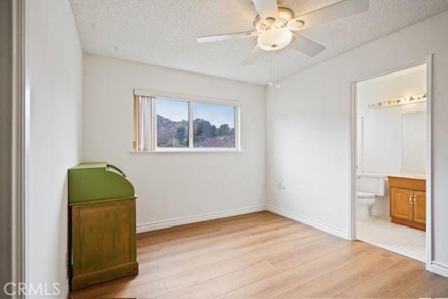 unfurnished bedroom featuring light wood-type flooring, baseboards, and a textured ceiling