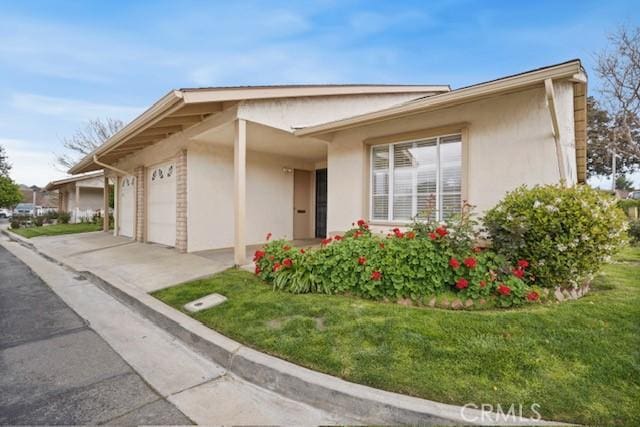 view of front facade featuring a front yard, an attached garage, stucco siding, and concrete driveway