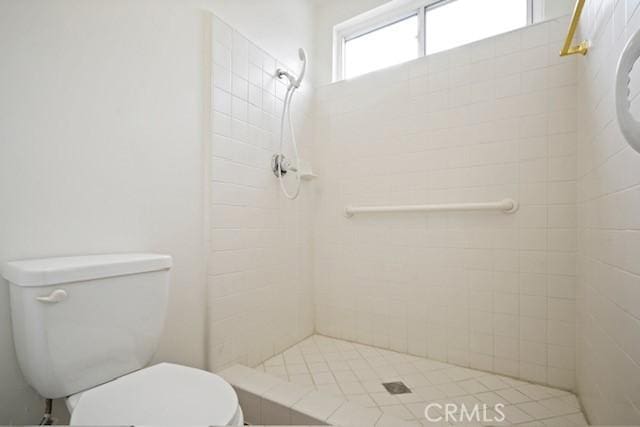 full bath featuring a tile shower and toilet