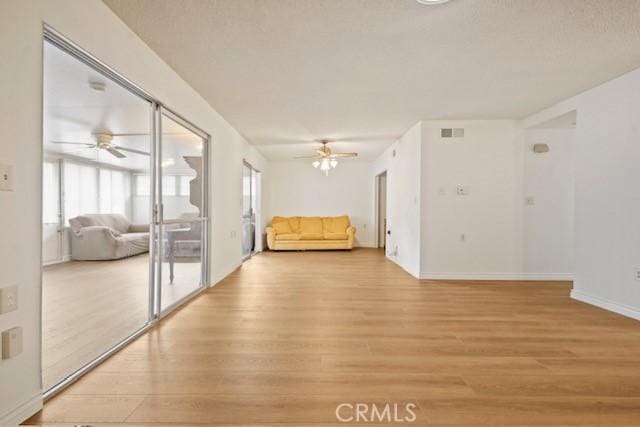 unfurnished living room with light wood-style floors, ceiling fan, baseboards, and visible vents