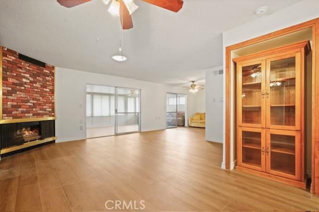 unfurnished living room with ceiling fan, wood finished floors, and a fireplace