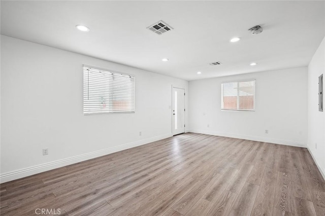unfurnished room with light wood finished floors, baseboards, visible vents, and recessed lighting