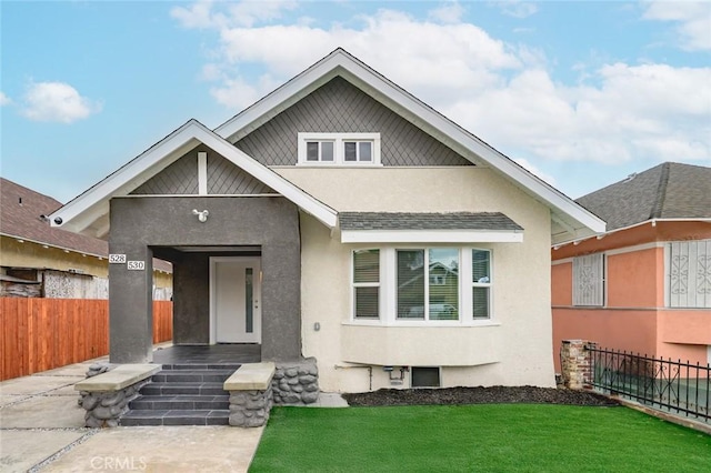 view of front of house with a front lawn, stucco siding, covered porch, and fence
