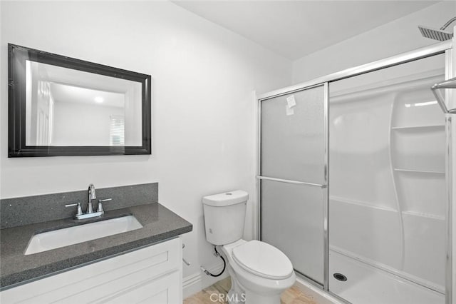 bathroom featuring a stall shower, toilet, and vanity