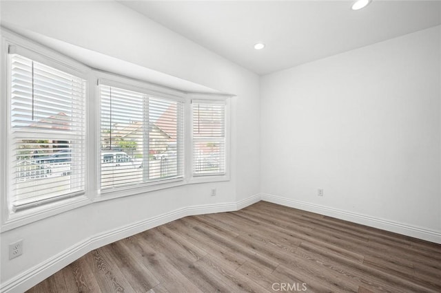 spare room with recessed lighting, baseboards, and wood finished floors