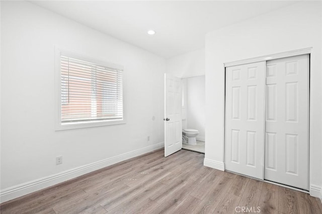 unfurnished bedroom featuring baseboards, a closet, light wood-style flooring, and recessed lighting