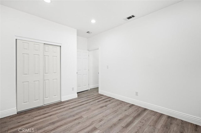 unfurnished bedroom featuring baseboards, visible vents, wood finished floors, and a closet