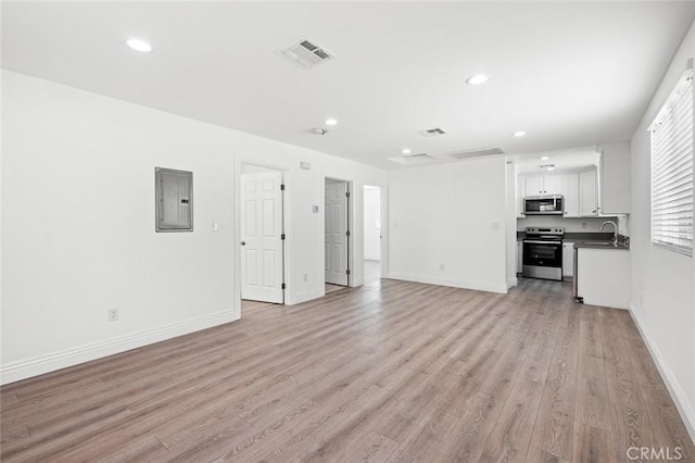 unfurnished living room with recessed lighting, visible vents, light wood-style floors, and electric panel