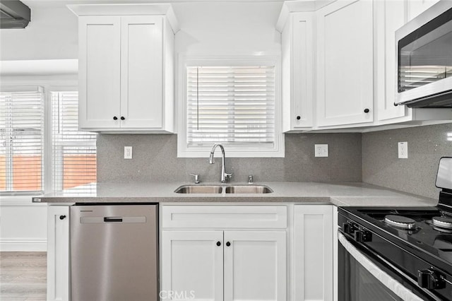 kitchen with white cabinets, light countertops, a sink, and stainless steel appliances