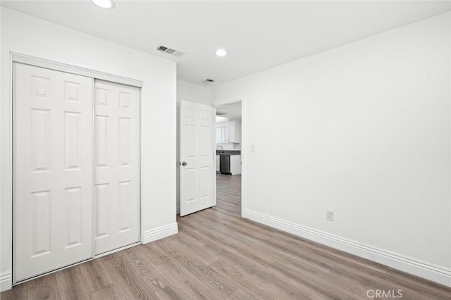 unfurnished bedroom with a closet, visible vents, baseboards, wood finished floors, and recessed lighting