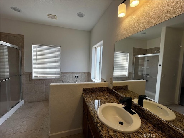 bathroom featuring tile walls, visible vents, tile patterned floors, vanity, and a stall shower