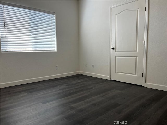 empty room featuring baseboards and dark wood-style flooring