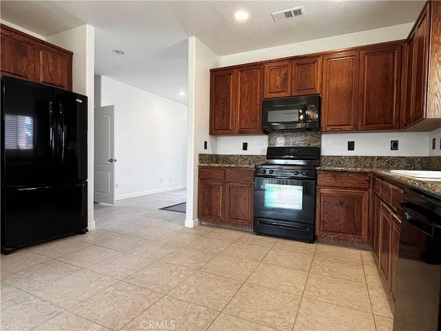 kitchen featuring baseboards, dark stone counters, light tile patterned flooring, visible vents, and black appliances