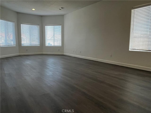 unfurnished room featuring dark wood-style floors, visible vents, recessed lighting, and baseboards