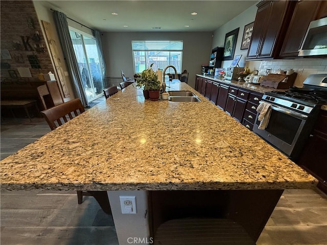 30130 Pine Needle Rd, Menifee, CA 92585 - kitchen featuring a sink, appliances with stainless steel finishes, a large island with sink, dark brown cabinets, and a kitchen breakfast bar