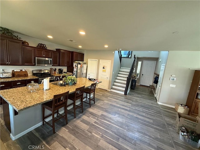 30130 Pine Needle Rd, Menifee, CA 92585 - kitchen featuring appliances with stainless steel finishes, dark wood-style flooring, a kitchen breakfast bar, a kitchen island with sink, and dark brown cabinets
