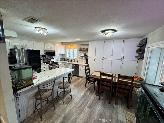 40451 Rome Beauty Way, Cherry Valley, CA 92223 - kitchen featuring stainless steel appliances, a breakfast bar area, wood finished floors, a peninsula, and a sink