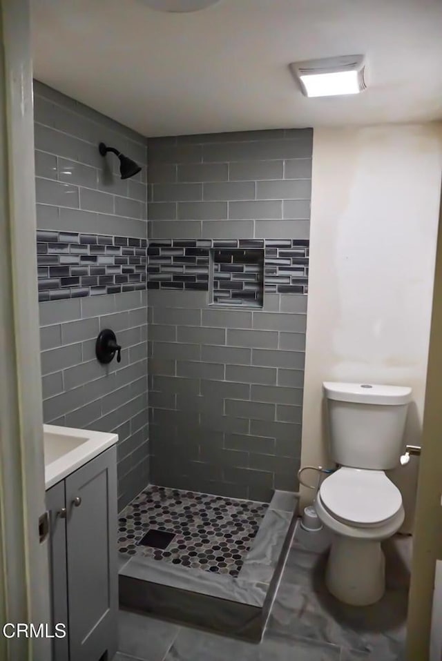 bathroom with toilet, vanity, and a stall shower