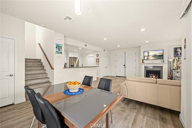 5402 Peck Rd, El Monte, CA 91732 - dining space with light wood-style flooring, stairs, a glass covered fireplace, and recessed lighting