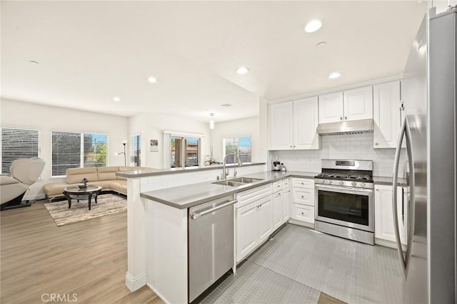 5402 Peck Rd, El Monte, CA 91732 - kitchen featuring stainless steel appliances, open floor plan, a peninsula, white cabinets, and under cabinet range hood