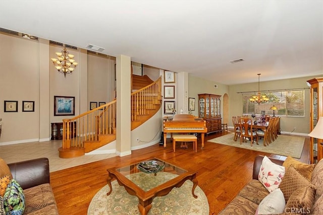 living room with a chandelier, stairway, baseboards, and wood finished floors