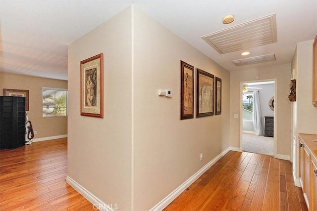 corridor with light wood-type flooring and baseboards