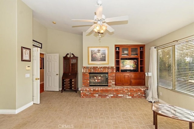 living area featuring vaulted ceiling, light colored carpet, a brick fireplace, ceiling fan, and baseboards