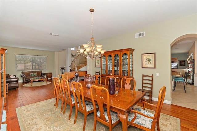 dining area featuring arched walkways, a chandelier, and hardwood / wood-style flooring