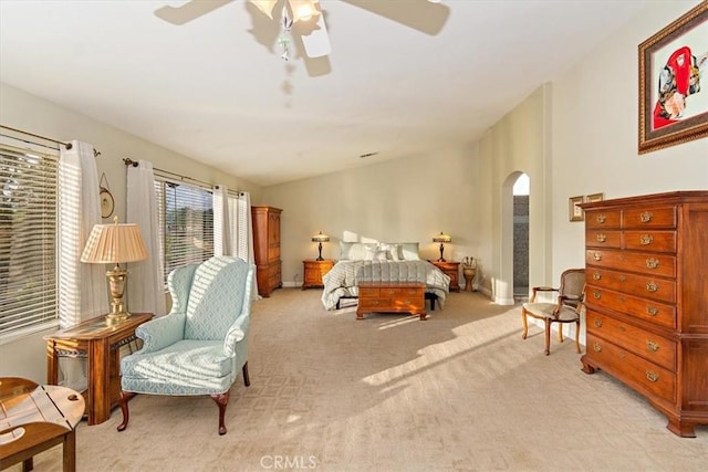 bedroom featuring arched walkways, light carpet, a ceiling fan, and baseboards