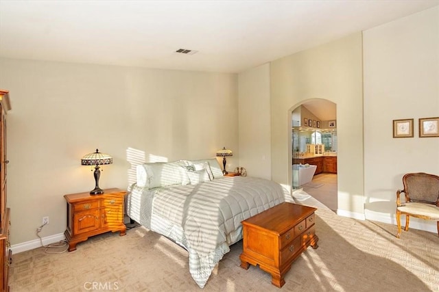 bedroom with arched walkways, light colored carpet, and baseboards