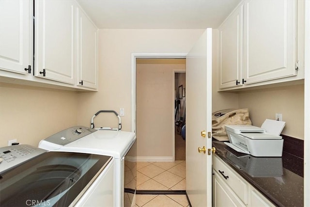 laundry area featuring cabinet space, washing machine and dryer, light tile patterned floors, and baseboards