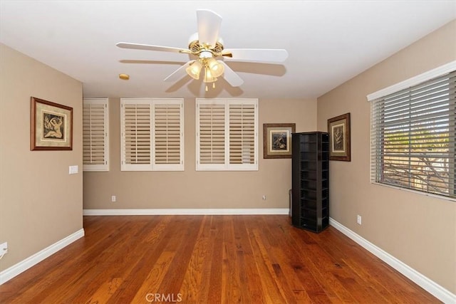 unfurnished room featuring ceiling fan, wood finished floors, and baseboards