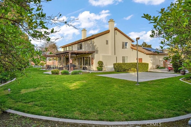 back of property with a patio area, a yard, a chimney, and stucco siding