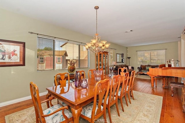 dining area featuring a chandelier, hardwood / wood-style floors, and baseboards