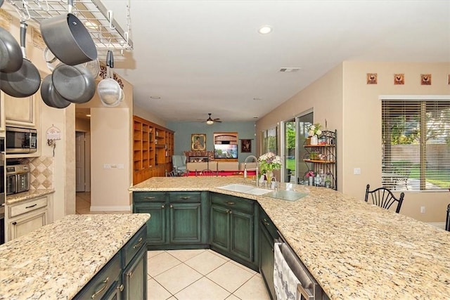 kitchen featuring a sink, stainless steel appliances, light tile patterned flooring, ceiling fan, and light stone counters