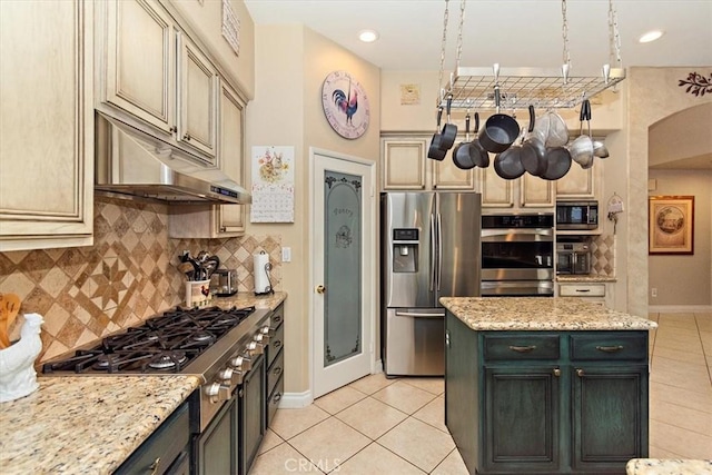kitchen with stainless steel appliances, light tile patterned floors, under cabinet range hood, decorative backsplash, and arched walkways