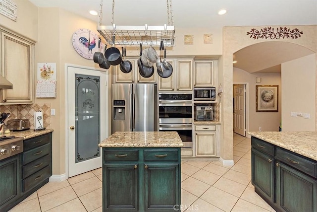 kitchen featuring stainless steel appliances, arched walkways, light tile patterned flooring, backsplash, and recessed lighting