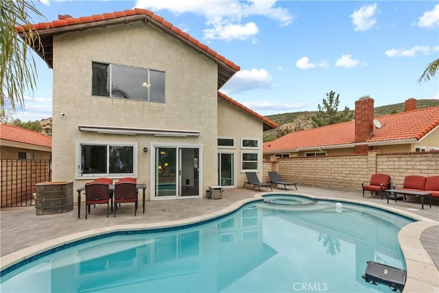 back of house with a fenced in pool, fence, stucco siding, an in ground hot tub, and a patio