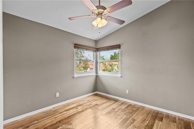 unfurnished room with vaulted ceiling, wood finished floors, and baseboards