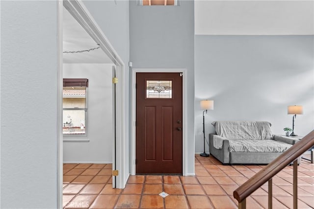 entryway with light tile patterned flooring, a towering ceiling, and baseboards